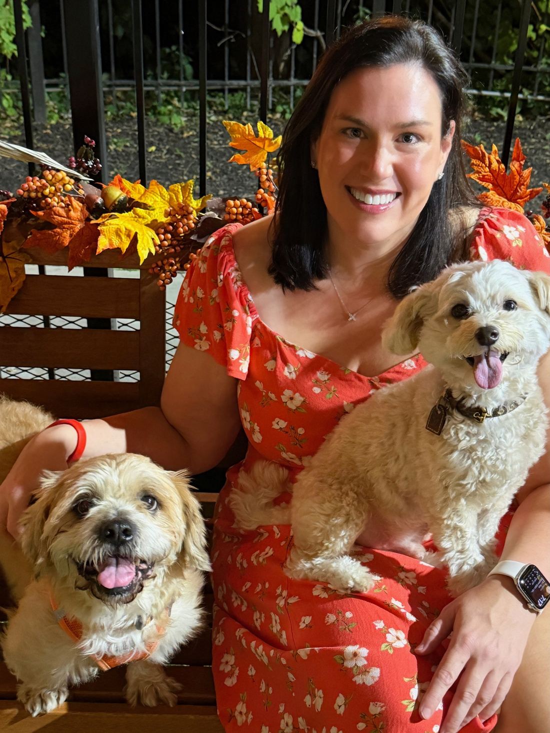 Jen on a fall-decorated bench with Cooper and Oscar